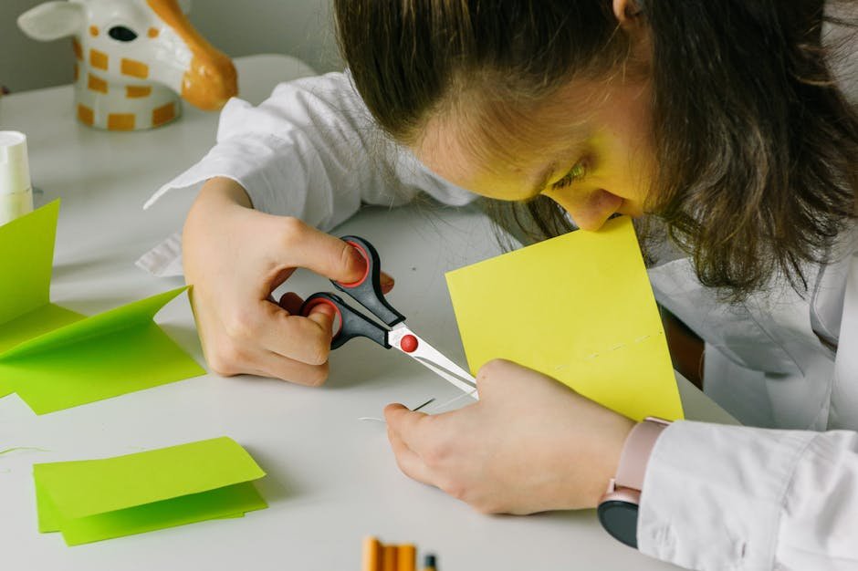 A young woman focuses on cutting colorful paper pieces for art and crafts at a table.
